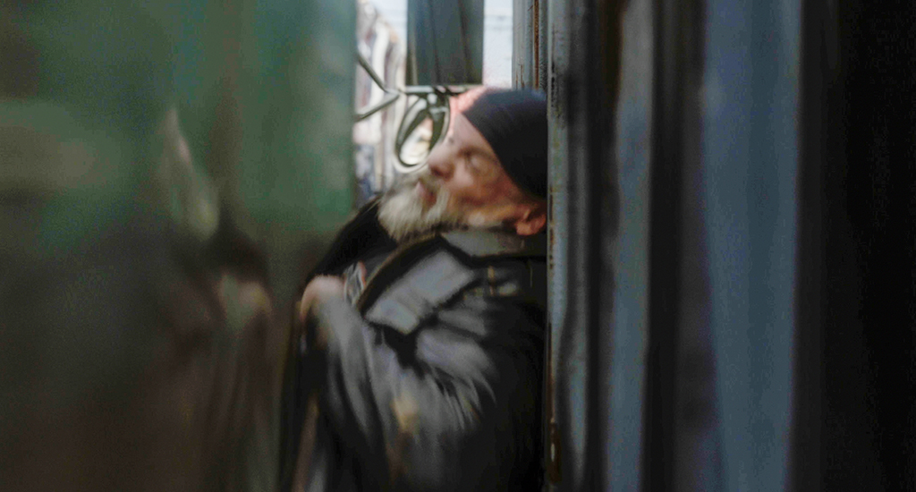 Grips compress a flat board against the actor to make look like he is being pushed against the dumpster by the CG truck. 