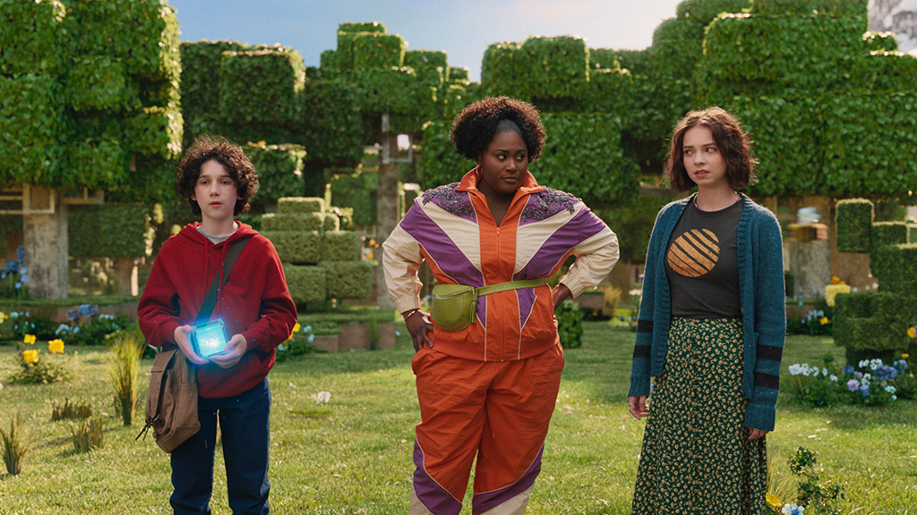 Cast members Sebastian Hansen, Danielle Brooks and Emma Myers stand in front of the Earth Portal Plateau environment. 